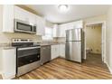 Bright kitchen with white cabinets, stainless steel appliances, granite countertops, and wood-look floors at 5822 Flori Ln, Orlando, FL 32808