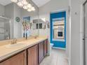 Bright bathroom boasting double sinks, spacious vanity, white tile flooring, and vibrant blue accent wall at 6636 S Goldenrod Rd # 116B, Orlando, FL 32822
