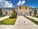 Beautiful townhome with a paver driveway, a two-car garage, and manicured landscaping at 812 Driving Range Ct, Reunion, FL 34747