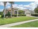 Inviting home exterior featuring stone accents, palm trees, manicured lawn, and a three-car garage at 9843 Nokay Dr, Orlando, FL 32836
