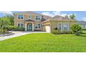Inviting exterior view of a tan two-story home featuring a manicured lawn and a spacious three-car garage at 14545 Braddock Oak Dr, Orlando, FL 32837