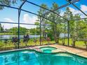 Sparkling blue pool with an attached spa and screened enclosure overlooking a tranquil lake at 1846 Branchwater Trl, Orlando, FL 32825