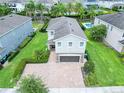A two-story home with a well manicured lawn and landscaping, surrounded by other homes and palm trees at 311 W Falls Dr, Kissimmee, FL 34747