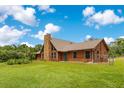Beautiful log home exterior featuring a manicured lawn and stone chimney on a sunny day at 5180 Garlanger Trl, Oviedo, FL 32765
