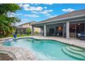Inviting backyard pool area featuring a lovely waterfall feature and a covered patio for outdoor relaxation at 595 American Holly Pl, Oviedo, FL 32765