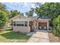 Inviting home exterior showcases a small front porch, attached garage, and a lush green lawn at 849 Driver Ave, Winter Park, FL 32789