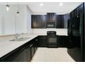 Modern kitchen featuring black appliances, dark cabinetry, and sleek countertops at 9069 Shepton St, Orlando, FL 32825