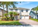 Two-story home featuring brick driveway, palm trees, well-kept lawn, and a convenient two-car garage at 9836 Old Patina Way, Orlando, FL 32832