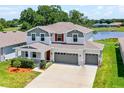 Two-story home with a three car garage, landscaped front yard, gray trim and water view at 10249 Spring Lake Dr, Clermont, FL 34711