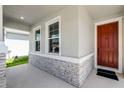 Stylish front porch with stone accents and a red front door for an inviting entry at 10249 Spring Lake Dr, Clermont, FL 34711