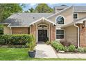 Close up of the home's entrance with a well-manicured lawn and mature trees at 10664 Spring Buck Trl, Orlando, FL 32825