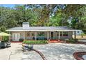 Charming single-story home features a brick facade, manicured front yard with mature trees, and a welcoming patio area at 1090 Braddock Rd, Deltona, FL 32725