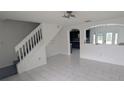 Bright living room featuring white tile floors and stairway access to second floor at 1321 Carey Glen Cir, Orlando, FL 32824