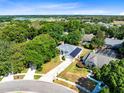 Aerial view of a beautiful home with solar panels surrounded by lush green trees and a serene lake in the distance at 1324 Saddleridge Dr, Orlando, FL 32835