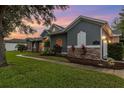 Charming exterior with stone accents and arched windows with a manicured lawn at 1333 Killbricken Cir, Ormond Beach, FL 32174