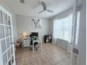 Bright office area with tiled floors, a ceiling fan, a large window, and a desk, offering a versatile workspace at 14400 Saint Georges Hill Dr, Orlando, FL 32828