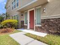 Inviting entryway with red front door, stone accents, and manicured landscaping at 1610 Mohegan Blvd, Kissimmee, FL 34744