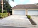 View of the garage and long driveway of this tan house with manicured landscaping at 2299 Hawks Cove Cir, New Smyrna Beach, FL 32168