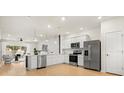 Modern white kitchen features stainless steel appliances, tile backsplash, and an island with pendant lights at 2949 Clever Ln, Winter Park, FL 32792