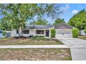 Inviting single-story home with a lush front yard, mature trees, and a two-car garage at 107 Hilltop Dr, Longwood, FL 32750