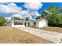 Charming one-story home with a long driveway, set against a backdrop of blue skies and lush trees at 1340 Bakersfield Ave, Deltona, FL 32725