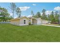 A single-story home with a large, well-manicured yard, mature trees, and a driveway leading to the garage at 13881 Sw 80Th Ave, Ocala, FL 34473