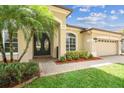 Front entrance of home featuring double glass front doors, two-car garage and lush landscaping at 14003 Sobrado Dr, Orlando, FL 32837