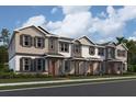 New townhomes feature neutral siding, dark shutters, covered porches, and manicured landscaping at 15345 Burgtheater Dr, Winter Garden, FL 34787
