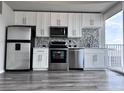 Modern kitchen with stainless steel appliances, white cabinets, and tiled backsplash at 155 S Court Ave # 2406, Orlando, FL 32801