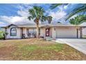 Charming single-story home with a vibrant red door and meticulously maintained landscaping showcasing curb appeal at 15628 Hidden Lake Cir, Clermont, FL 34711