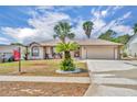 Inviting single-story home with a two-car garage and well-manicured landscaping featuring charming palm trees at 15628 Hidden Lake Cir, Clermont, FL 34711