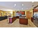 Gourmet kitchen featuring dark wood cabinets, granite countertops, stainless steel appliances, and an island at 2921 Falconhill Dr, Apopka, FL 32712