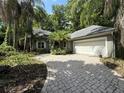Charming home with a brick driveway and lush tropical landscaping surrounding the property at 4107 Gabriella Ln, Winter Park, FL 32792