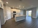 Modern kitchen features white cabinets, stainless appliances, large island, and sliding glass doors at 5262 Teirgarten St, St Cloud, FL 34771