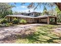 Charming home featuring mature landscaping, stone accents, and a covered portico at 5655 Oak Hollow Ln, Oviedo, FL 32765