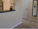 Hallway with neutral carpet leads past a closet and partial kitchen view with a breakfast bar at 581 Brantley Terrace Way # 302, Altamonte Springs, FL 32714