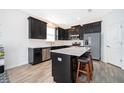 Modern kitchen featuring black cabinets, stainless steel appliances, and a large island with countertop seating at 6984 Dilly Lake Ave, Groveland, FL 34736