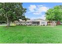 Landscaped single-story home with a lush lawn, mature trees, and a quaint screened front porch at 701 Lakeshore Blvd, St Cloud, FL 34769