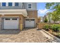 Attached garages feature brick facade, well manicured landscape, and a paved driveway at 7573 Laureate Blvd # 1-404, Orlando, FL 32827