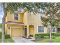 Inviting two-story home with a yellow exterior, white trim, covered entry, and attached garage at 8989 Cuban Palm Rd, Kissimmee, FL 34747