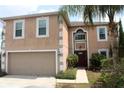 Two-story home with attached two-car garage, neutral stucco siding, decorative trim, and covered front entry at 1009 Ronlin St, Haines City, FL 33844
