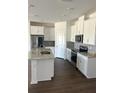 Modern kitchen with white cabinets, granite countertops, stainless steel appliances, and hardwood floors at 1141 Lakeshore Breeze Pl, Kissimmee, FL 34747
