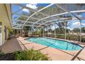 Backyard pool surrounded by a screened-in patio, landscaping, and an outdoor seating area at 1190 Pecan St, Kissimmee, FL 34744