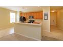 Open kitchen with a breakfast bar, wood cabinets, black appliances, and tile flooring, perfect for entertaining and cooking at 1630 Common Way Rd # 203, Orlando, FL 32814