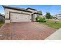 Red brick driveway of a single-story home with a two-car garage at 17199 Hickory Wind Dr, Clermont, FL 34711