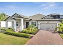 Charming single-story home showcasing a brick driveway, well-maintained landscaping, and a welcoming entrance at 17333 Hickory Wind Dr, Clermont, FL 34711