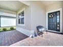 Cozy front porch featuring a decorative wreath, bench with pillows, and stylish blue and white ceramic vases at 17333 Hickory Wind Dr, Clermont, FL 34711