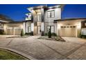 Exterior home featuring a modern design, three-car garage, and illuminated architectural details at twilight at 182 N Phelps Ave, Winter Park, FL 32789