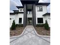 Impressive modern home with glass front door, black accents, and a geometric paver walkway at 182 N Phelps Ave, Winter Park, FL 32789