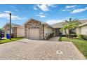 Exterior view showcasing the home's well-maintained lawn, brick driveway, and attached two-car garage at 2640 Shelby Ruth Pl, St Cloud, FL 34769